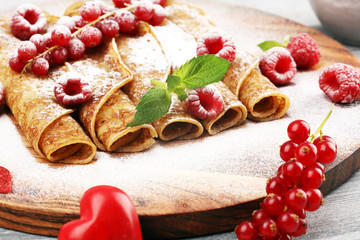 Delicious Tasty Homemade crepes or pancakes with raspberries and mint on rustic background