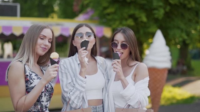 Medium close up handheld shot of three beautiful sexy ladies eating ice cream and laughing