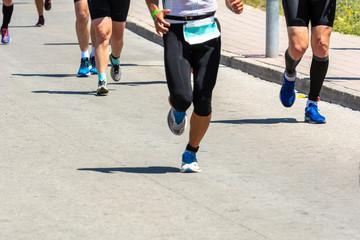 Marathon running race, people feet on city road.