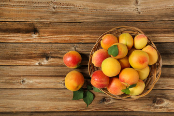 Sweet apricots in basket on brown wooden table