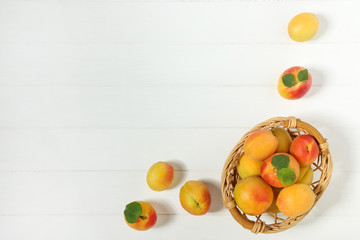 Sweet apricots with green leafs in basket on white wooden table