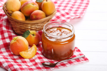 Jam in jar and apricots on white background