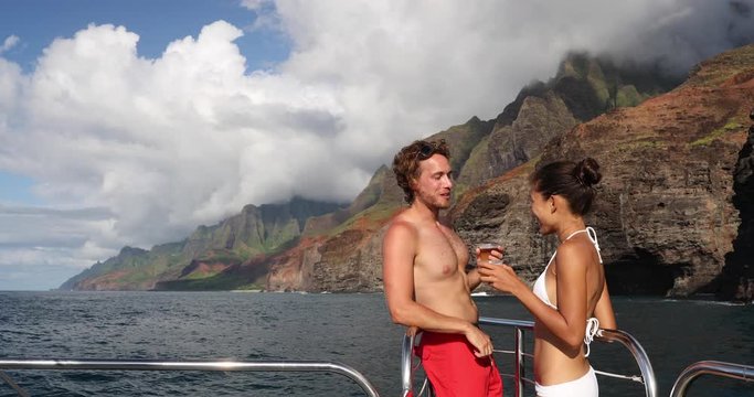 Travel couple on Hawaii cruise ship boat. Tourists People on Na Pali Coast of Kauai, Hawaii Tourist Couple looking at in NaPali, a famous Hawaiian travel destination while laughing having fun.