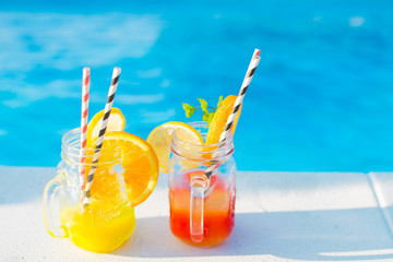 Glasses with tasty cocktails near swimming pool