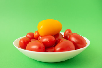 red tomatoes in white plate on green background