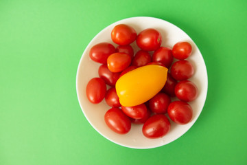 red tomatoes in white plate on green background