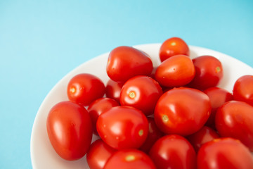 red tomatoes in white plate on blue background