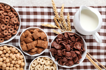 Various corn flakes with milk in jar and wheat ears on napkin