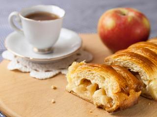 Sliced apple pie with an apple and a cup of coffee lies on the table