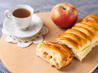 Sliced apple pie with an apple and a cup of coffee lies on the table