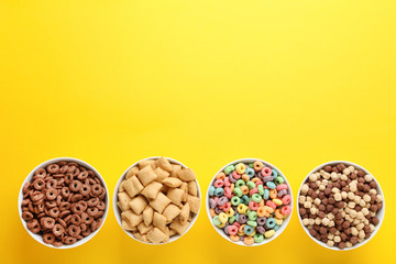 Various corn flakes in bowls on yellow background