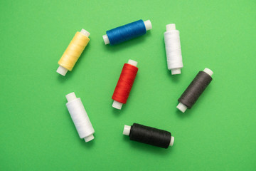 Set of sewing threads beautiful color (blue,yellow, green, white, black) on green background with space for text