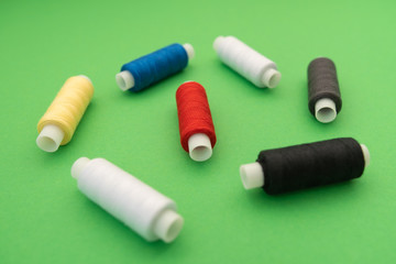 Set of sewing threads beautiful color (blue,yellow, green, white, black) on green background with space for text