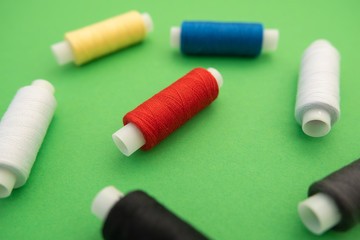 Set of sewing threads beautiful color (blue,yellow, green, white, black) on green background with space for text