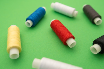 Set of sewing threads beautiful color (blue,yellow, green, white, black) on green background with space for text