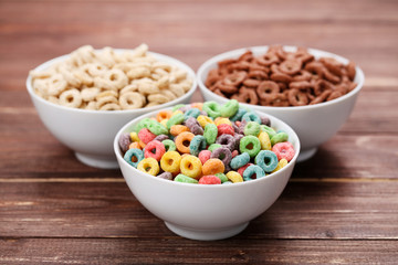 Various corn flakes in bowls on brown wooden table