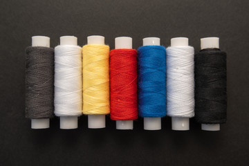 Set of sewing threads beautiful color (blue,yellow, green, white, black) on black background with space for text