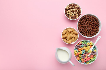 Various corn flakes with milk in jar on pink background