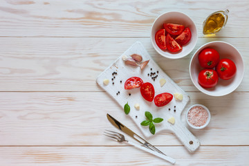 Naklejka na ściany i meble Beautiful fresh raw tomatoes, basil and garlic. Top view, close-up on white wooden background