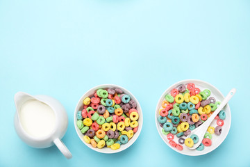 Colorful corn rings in bowls with milk and spoon on blue background
