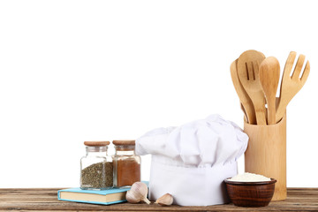 Chef hat with spices in jars, garlic and flour on brown wooden table