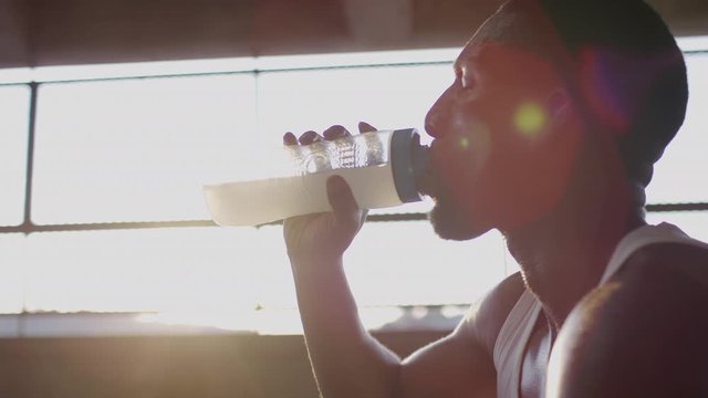 Sporty male drinking his recovery formula after a workout, in slow motion 