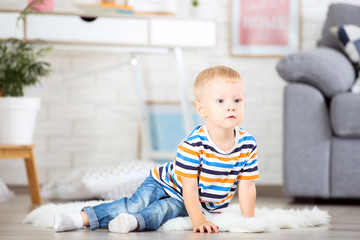 Fototapeta premium Little boy sitting on white carpet at home