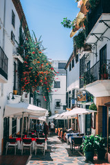 Cosy narrow street with restaurants and flowers in Marbella old town, Spain
