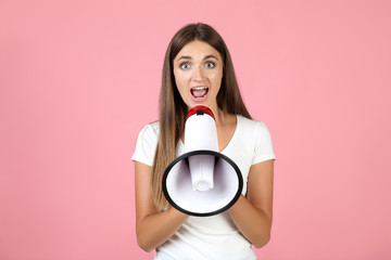 Young woman with megaphone on pink background