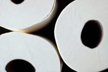 White toilet paper rolls and other home related objects against a white wall. Copy space.
