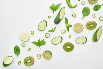 top view of fresh cucumbers, kiwi, limes, peppers and greenery