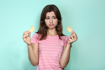 Young woman with potato chips on mint background