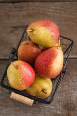 Fresh pears in the basket on the wooden background