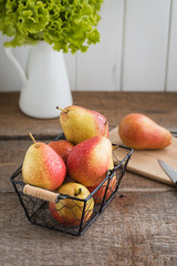Fresh pears in the basket on the wooden background