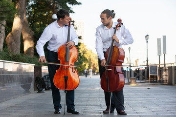 Cellist musician group perform music in the street, close up man playing violin