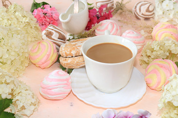 Flowers, cupcakes and a cup of coffee on the desktop.. Break at work in the office in comfortable conditions, the comfort of our home