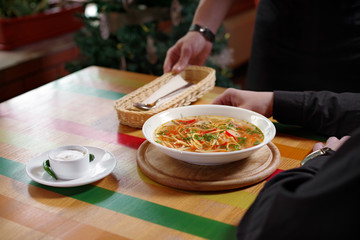 Man was served a bowl of soup with chicken, vegetables and noodles, a with sour cream and a spoon. Traditional Russian or Moldavian, Romanian or Ukrainian food is called Zama.