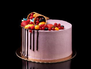 Pink fruit cake with a waffle cone. On a black background.