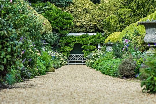 Traditional landscaped English garden path with lush flowering bushes.