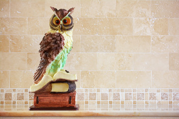 Owl as symbol of wisdom and knowledge. Decorative item, statuette of owl on stack of books.