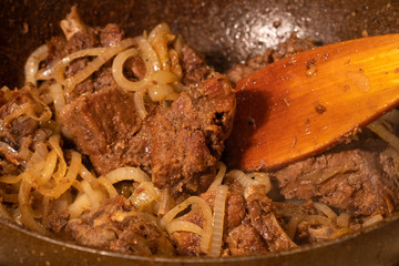 Fry lamb slices in vegetable oil with onions. Home-made meat.