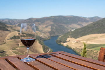 Glass of red wine or port for tasting above the hillsides of the Douro valley in Portugal
