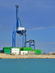 Fototapeta na wymiar Crane lifting shipping container on cargo port harbour terminal