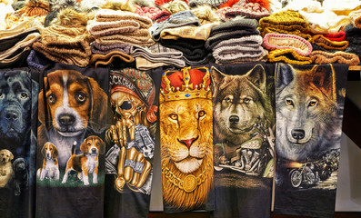 Towels with animal motifs and hats on a market stall.