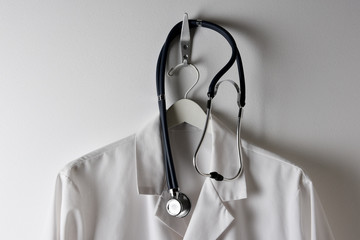Closeup of a Doctors White Lab Coat Hanging on a Hook with Stethoscope, horizontal.