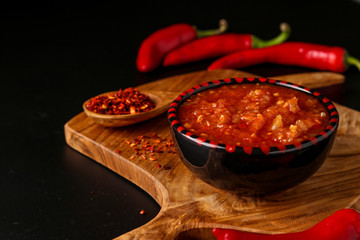 Traditional Maghrebi hot chili pepper sauce paste harissa on dark background, Tunisia and Arabic...