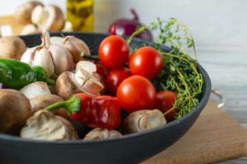 Fresh organic vegetables, tomatoes, mushrooms, peppers and thyme in frying pan, close up