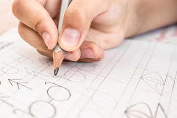 Schoolboy writing close-up. Pencil in the hand of children.