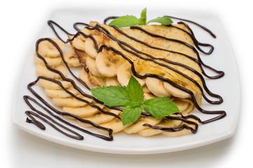 Crepes with chocolate cream and banana on white background.