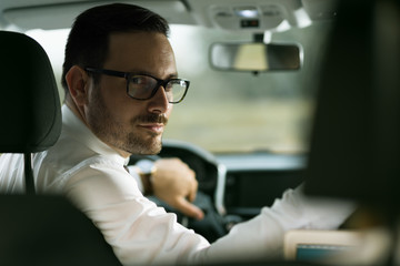 Young businessman reversing while driving a car